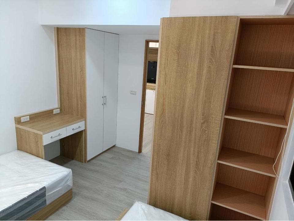 1) 照片顯示一個簡約的房間,房間裡有木質的衣櫃,書櫃,床以及書桌