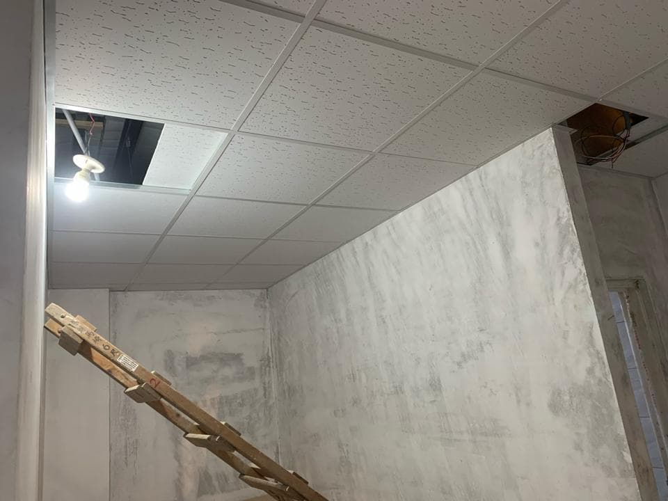 1) 照片顯示一個房間的內部,房間的天花板上有天花板磚,一個燈光照亮了房間,牆壁是光滑的