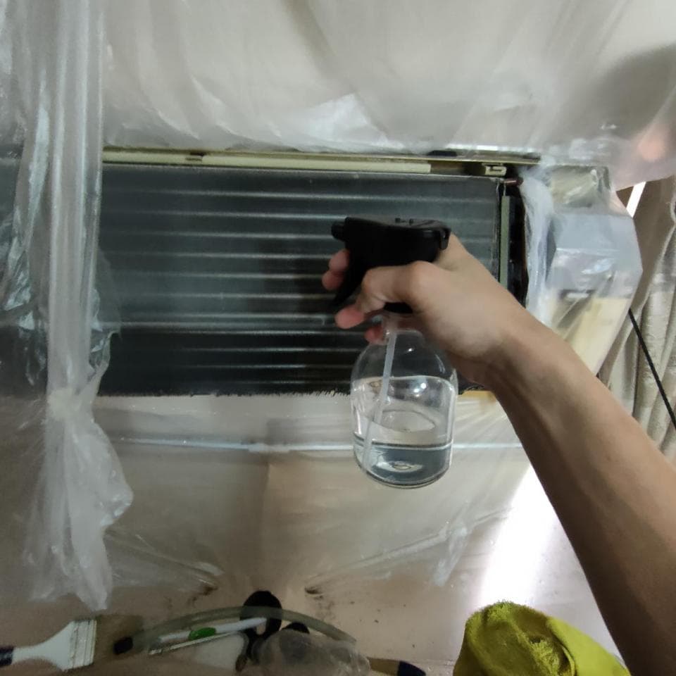 1) 照片顯示一個人在用噴霧瓶清潔空調