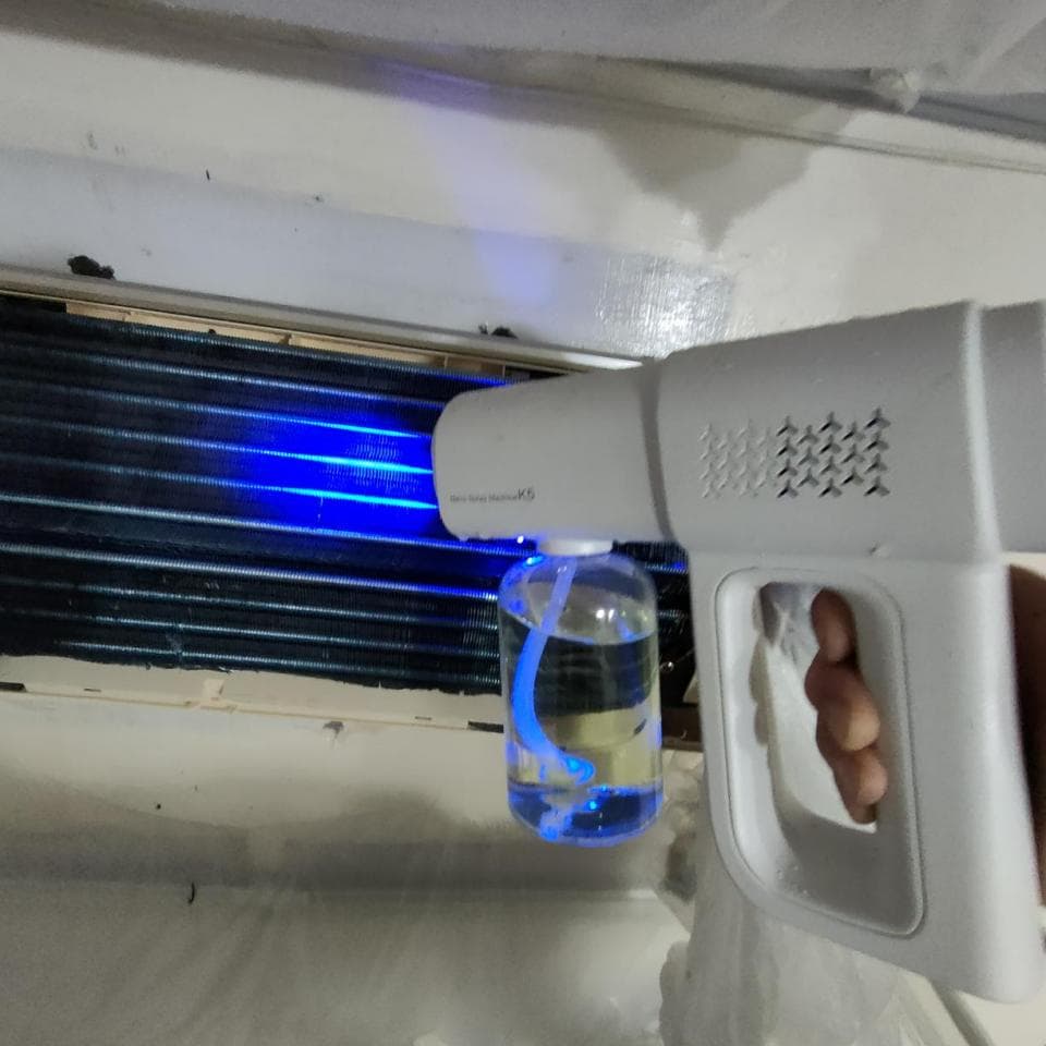 1) 照片顯示一個白色噴霧器,噴嘴對著一個冷氣機的蒸發器,蒸發器上有藍色的光