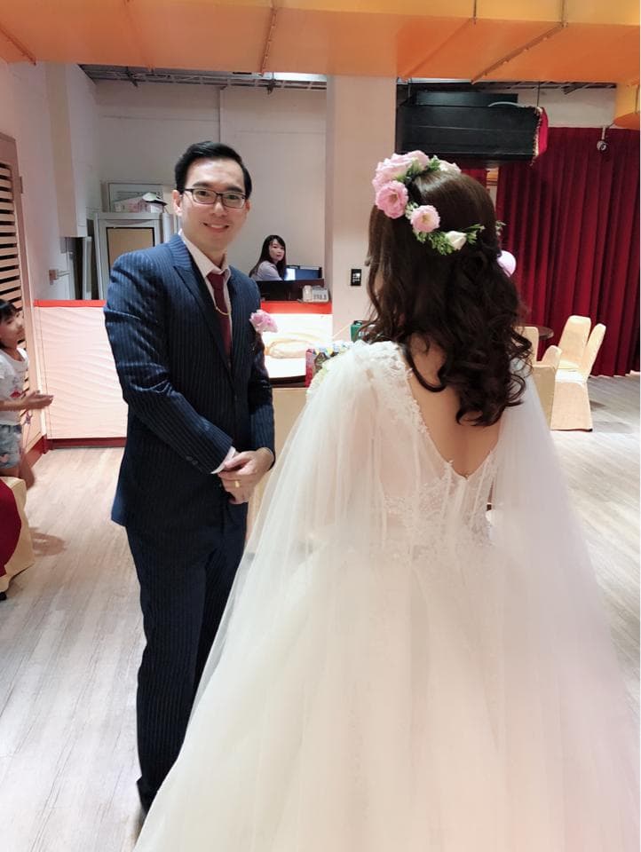 這張照片是一對新人在婚禮現場,新郎穿著黑色西裝,新娘穿著白色婚紗。