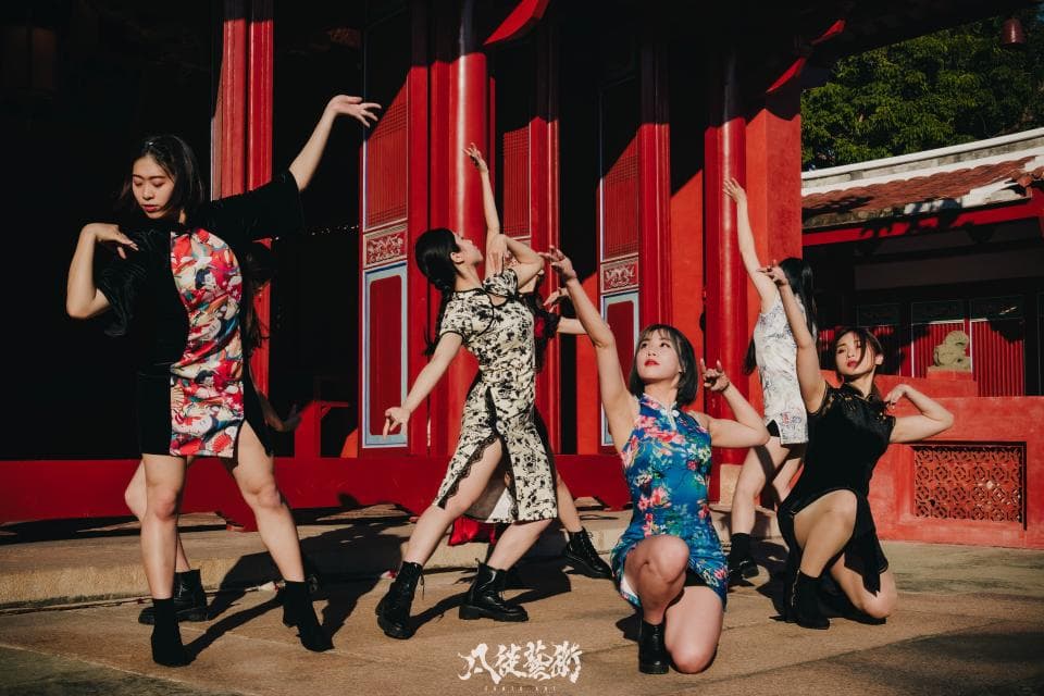 這張照片是五個穿著傳統服裝的年輕女性在一個紅色的建築物前跳舞。她們看起來很開心,充滿活力,這展現了中國傳統文化的魅力。