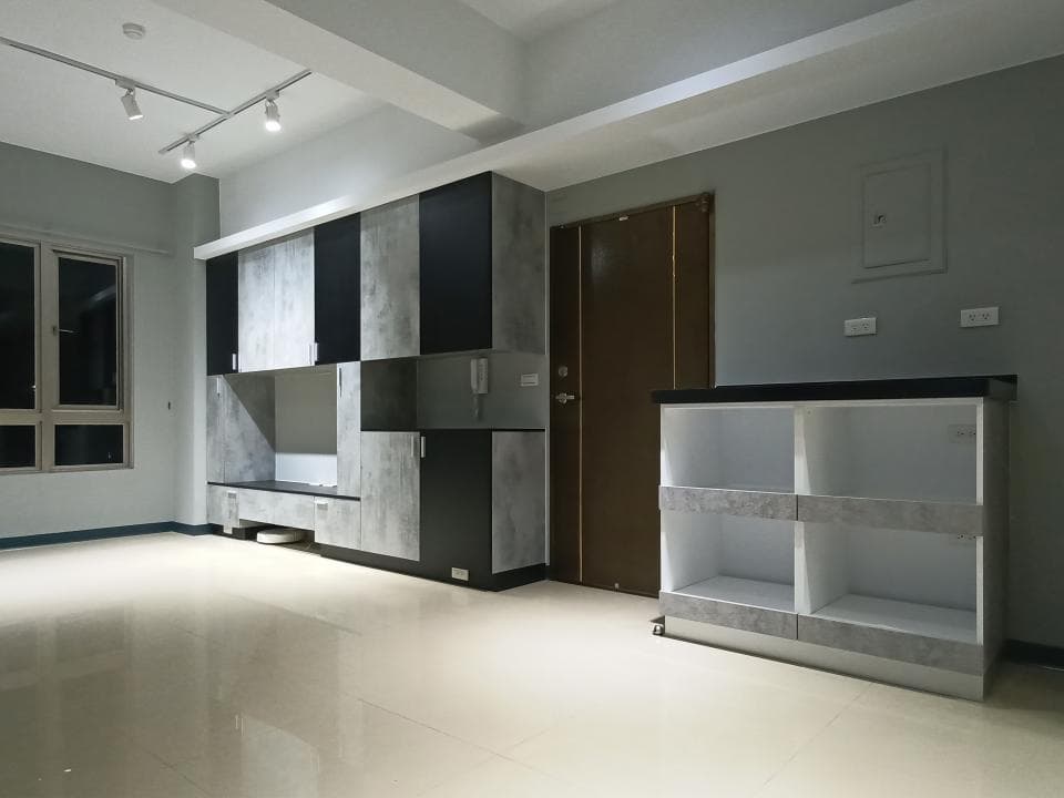 這張照片是一個現代化的客廳,最重要的是牆上的一個大型儲物櫃,它以灰白色和黑色為主色調,並以白色隔板分隔成多個區域。櫃子設計簡單,卻能提供充足的儲物空間。