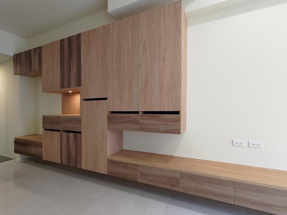 這張照片是一間現代化的客廳,重點是牆上的木質櫃子,它擁有許多層架和抽屜,可以放置許多物品,並增添空間的現代感。