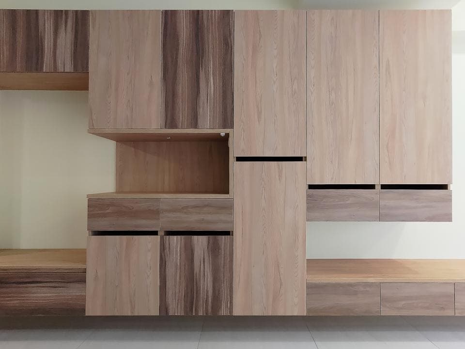 這張照片是一組木製的櫥櫃,它們被設計成一個整體的儲藏系統,並以不同的層級和尺寸排列。每個櫥櫃都具有獨特的木紋,為這個空間增添了溫暖和自然的氣息。