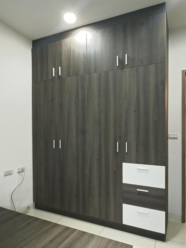 這張照片是一個現代化的衣櫥,它有許多抽屜和門。這些抽屜和門都由深色的木頭製成,看起來很時尚。衣櫥的設計很簡潔,但卻很實用。