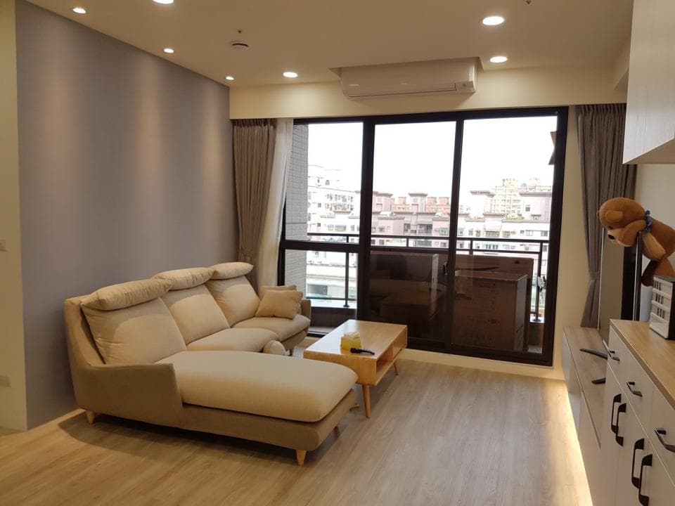 1) 照片顯示一個現代化的客廳,裡面有一張沙發、一張茶几和一個窗戶,窗外可以看見城市景觀