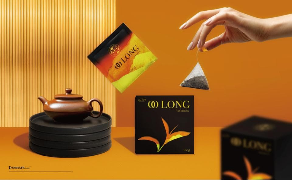 這張照片是 一個茶壺放在一個黑色木盤上,盤子上放著茶包。茶包上印著 “O LONG” 的字樣。茶壺旁邊放著一盒茶葉,盒子上也印著“O LONG” 字樣。茶葉包裝設計精美,茶壺造型古樸,營造出濃厚的茶文化氛圍。
