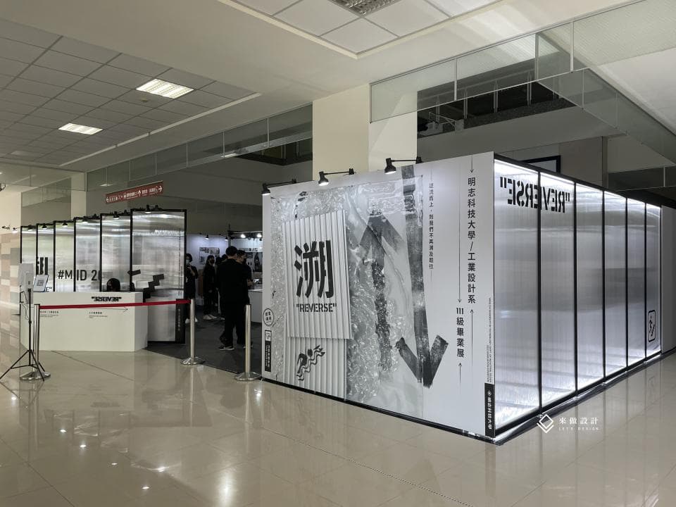 這張「展覽」的照片是現代風格的展覽空間,背景是白色牆面,前方展示著一個大型的展覽裝置,裝置上印有「REVERSE」的字樣。