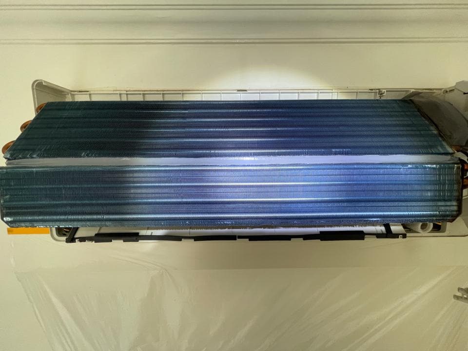 1) 照片顯示一個空調的內部,它有一個藍色的金屬格柵和白色的塑膠