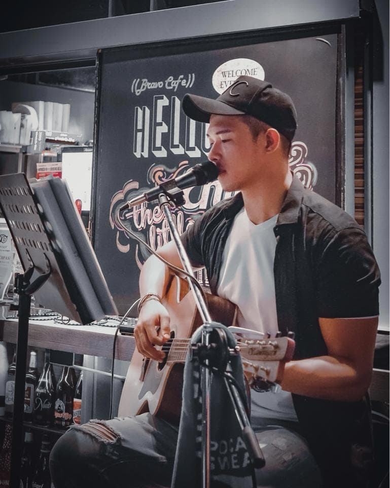 這張照片是一個男子正在酒吧里彈奏吉他唱歌。