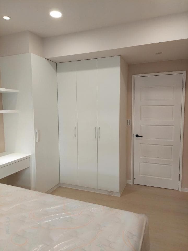 這張照片是一個簡約的臥室,最顯眼的是一個白色的衣櫃,它佔據了牆壁的一大部分,看起來很實用。