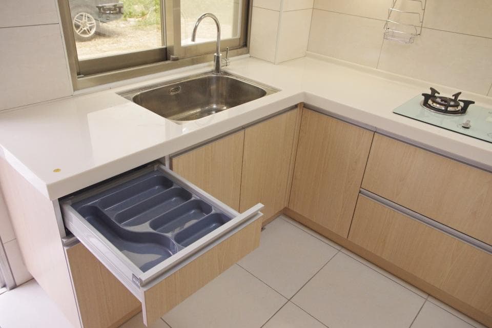 這張照片是廚房水槽下的抽屜,裡面放著一個灰色塑膠的餐具收納盒。