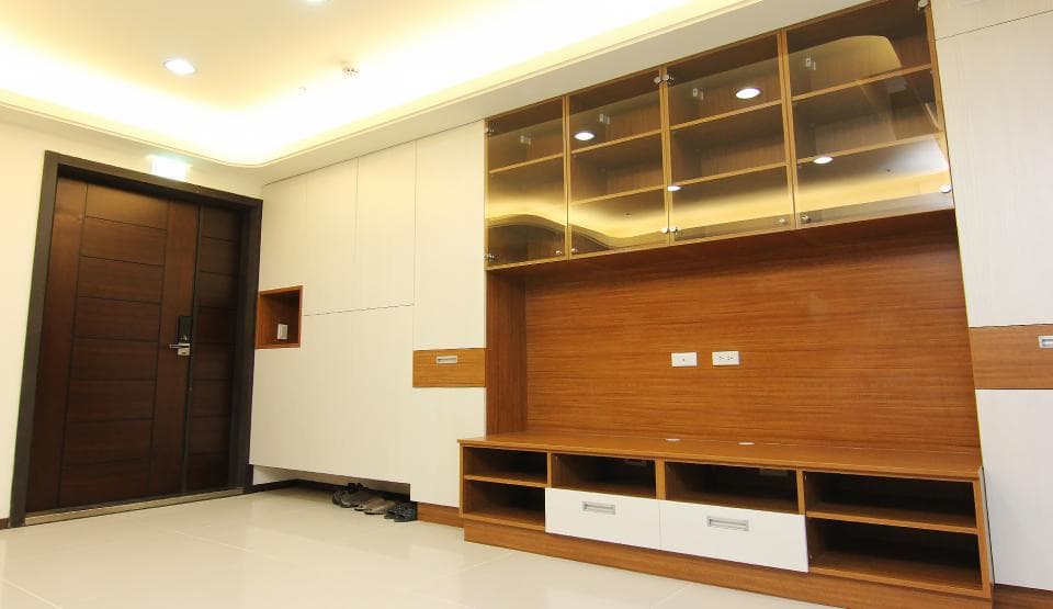 這張照片是一個現代化的客廳,最醒目的地方是牆上的電視櫃。電視櫃採用木質紋理,搭配玻璃門和抽屜,設計簡約大方。