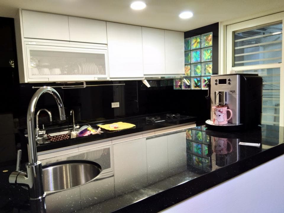 這張照片是一個現代化的廚房,最重要的是黑色大理石流理台,上面有一個咖啡機和一個水龍頭。流理台上的黑色大理石紋路非常明顯,呈現出高貴的質感。