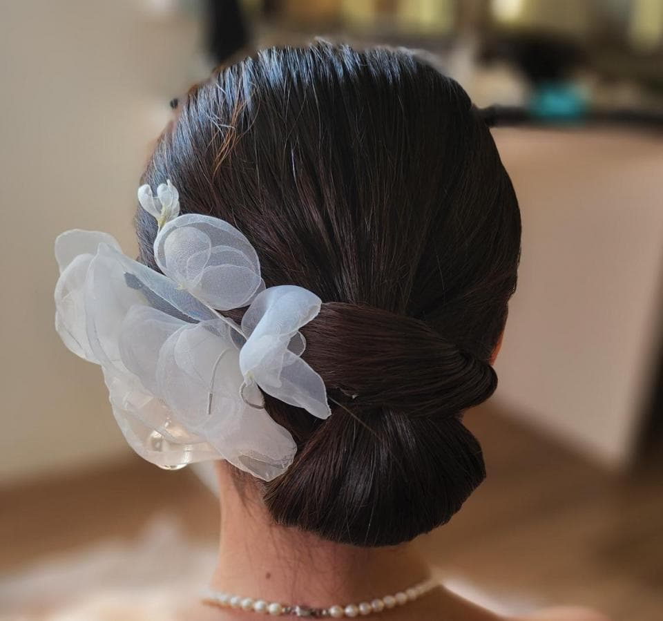 這張「新娘」的照片是一個女性,她穿著一件白色的禮服,她的頭髮盤成一個髮髻,髮髻上有一個白色的花朵。