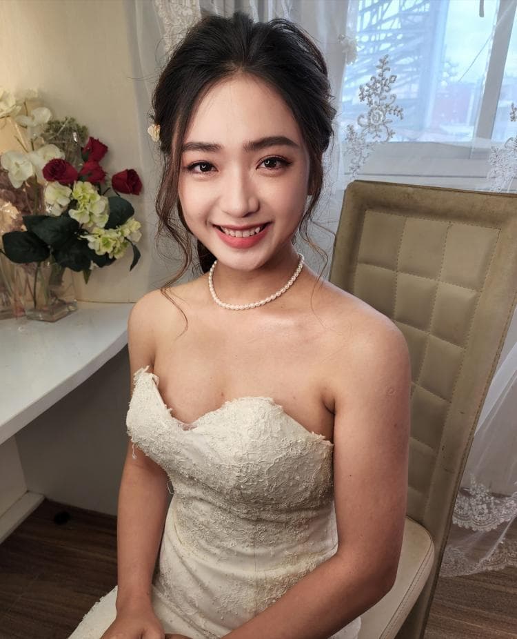 這張婚紗照是一個穿著白色婚紗的新娘,她戴著珍珠項鍊,笑容甜美,看起來很幸福。