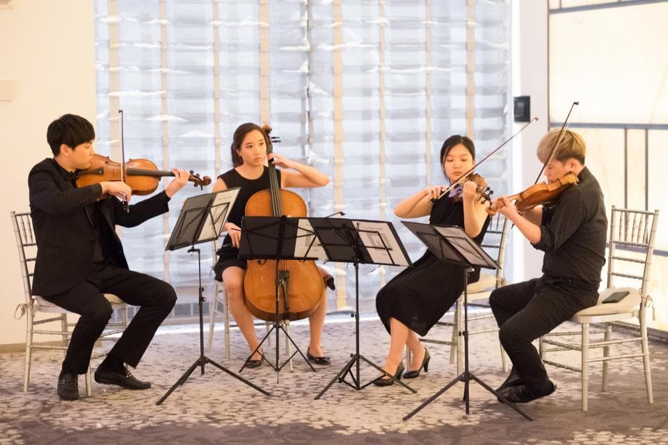 這張照片是一群人正在演奏古典音樂,四個人分別演奏小提琴和大提琴,他們看起來很專注,演奏得非常投入。