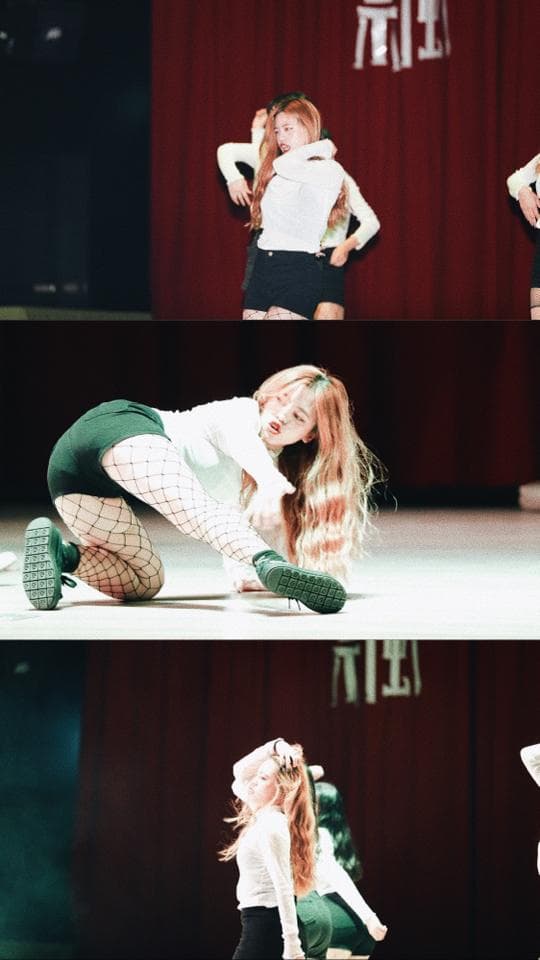 這張照片是三位女生在舞台上跳舞,其中一位女生穿着黑色短褲和白色上衣,她正跳著舞蹈動作,她的腿和腳踝交叉,看起來非常靈活。