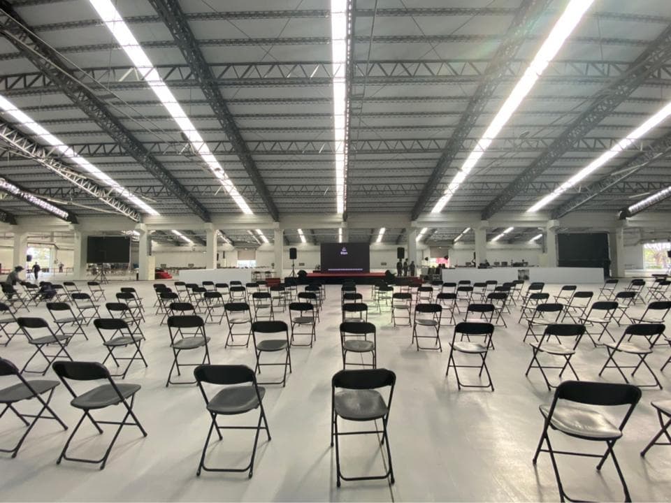 這張照片是一個大型的空曠空間,空間裡擺滿了成排的黑色摺疊椅,似乎是準備舉辦活動或會議的場地。