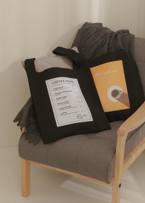 這張「咖啡店」的照片是,一個黑色帆布包,上面印著咖啡菜單,放在沙發上。