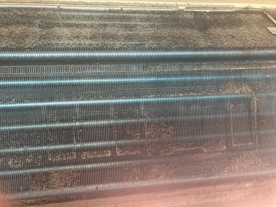 這張照片是一個佈滿灰塵的冷氣機散熱片。散熱片上積滿了灰塵和污垢,影響了冷氣機的散熱效果。