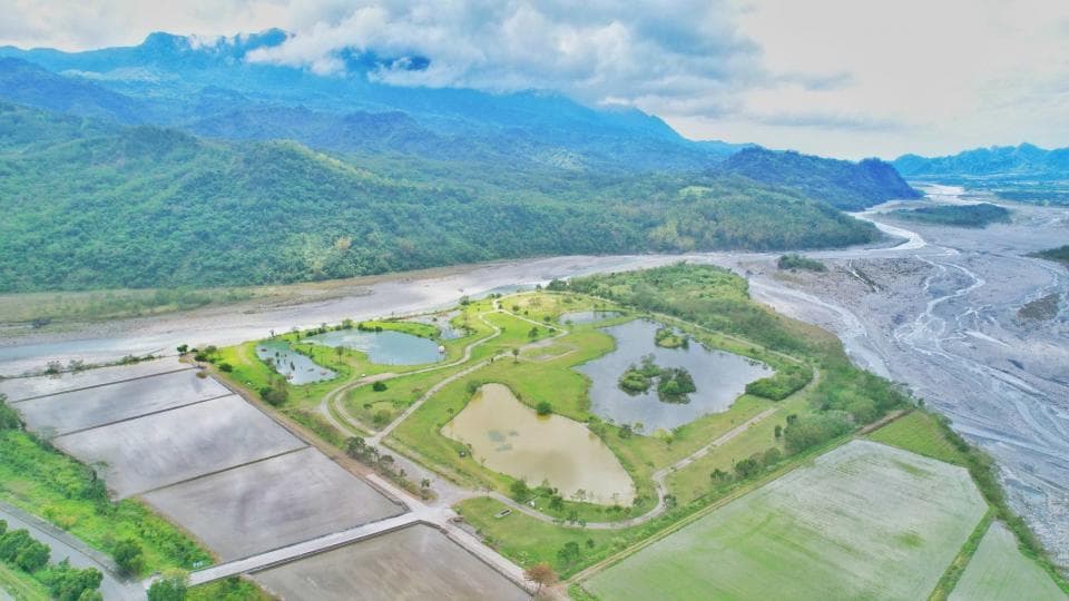 這張「空中」的照片是一片綠色山谷,中間有一條河流蜿蜒流過。山谷裡有綠色的草地,以及幾個小池塘。