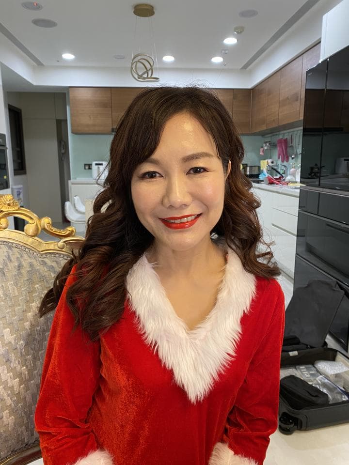 這張「一位女士穿著紅色的聖誕服,站在金色椅子旁」的照片是。