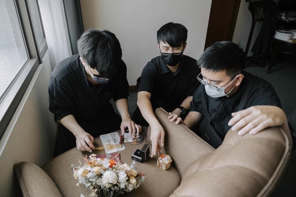 這張「三個人坐在沙發上,其中一個人拿著一個小盒子」的照片是。