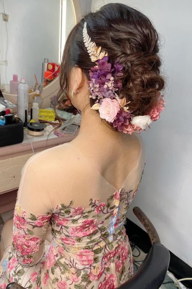 這張照片是一個女孩,她穿著一件印有花朵圖案的洋裝,頭髮上戴著花朵裝飾。