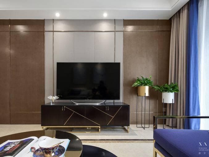 這張「客廳」的照片是一間現代化的居家空間,其中有一個大型的電視牆,電視下方是黑色的電視櫃,兩側有植物,看起來非常舒適。