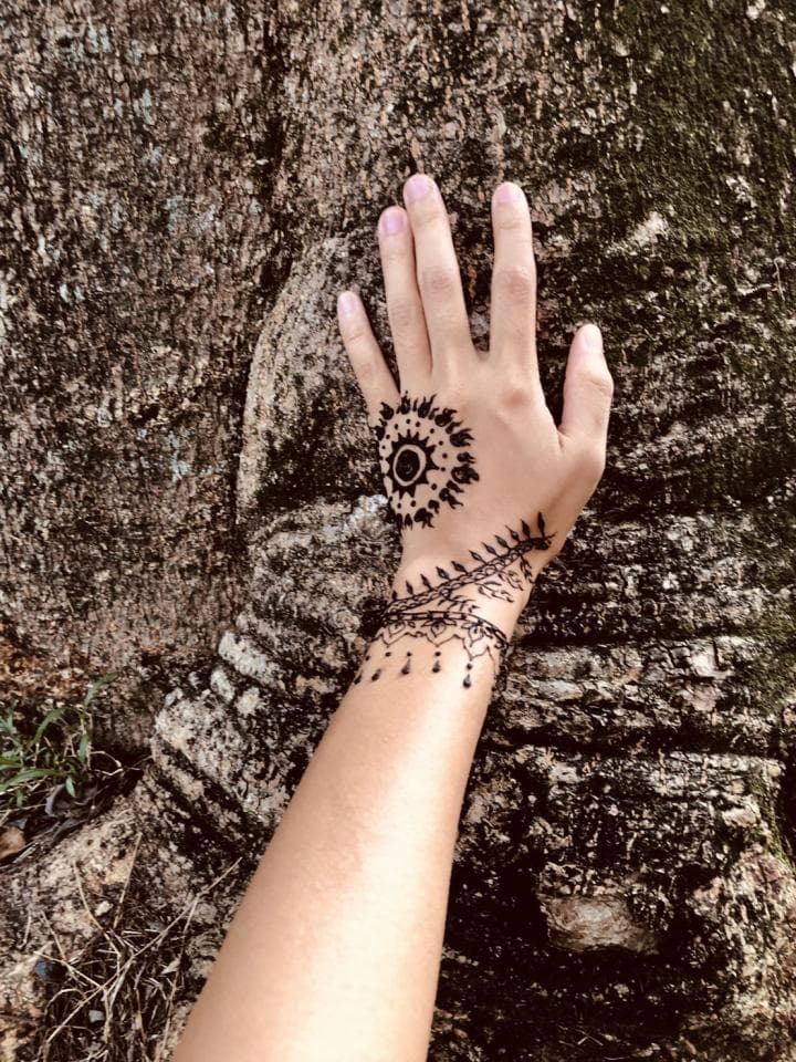 這張照片是一隻手放在樹皮上,上面畫著精美的黑色圖案。