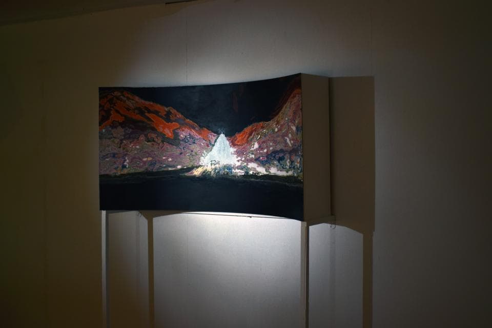 這張「風景畫」的照片是一個山景,畫面中有紅色的山脈和綠色的植物,前景是一個白色的建築物。