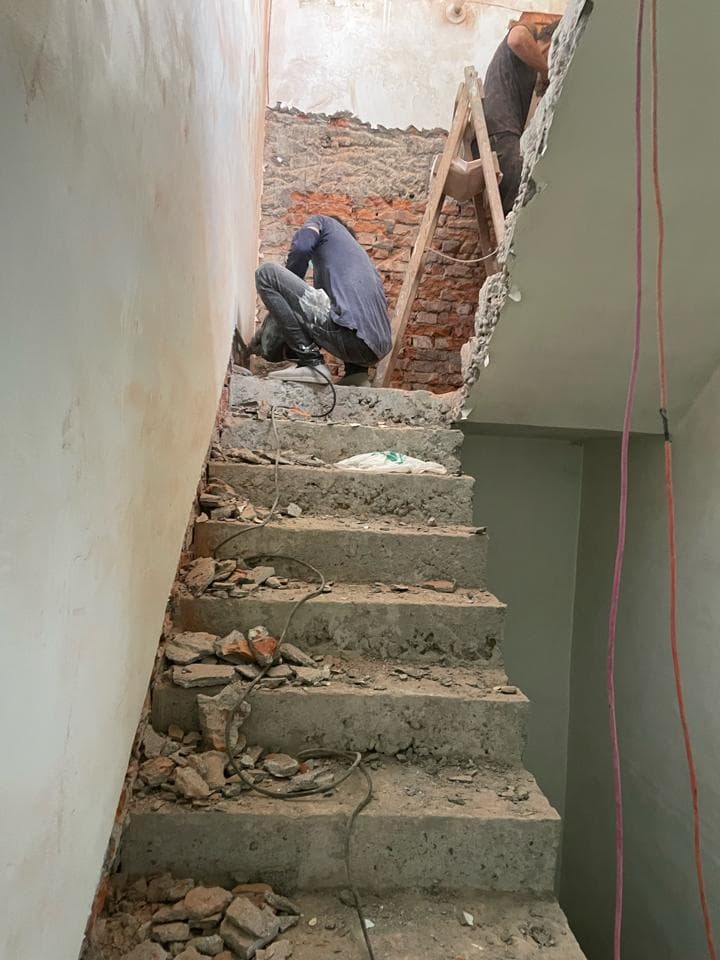 1) 照片顯示一棟建築物正在施工中,有一名工人站在梯子上,另一名工人則在樓梯上作業