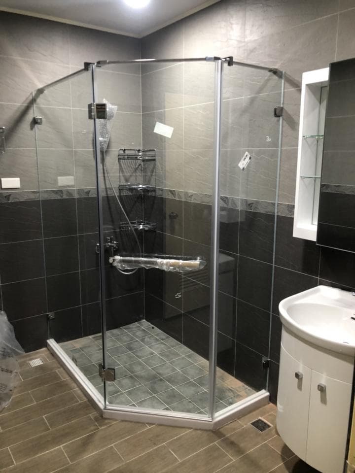 這張照片是一個現代化的浴室,最重要的是一個有玻璃門的淋浴間,淋浴間有白色瓷磚地板和黑色瓷磚牆。