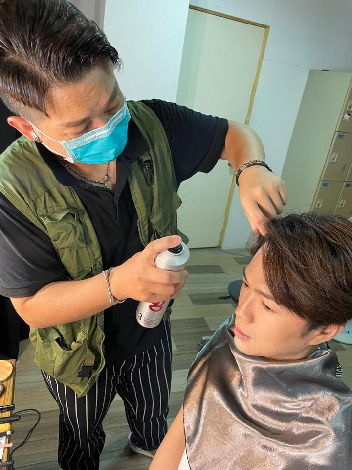 這張照片是兩個人在做頭髮,其中一個人在用噴霧器噴髮膠,另一個人在等待。