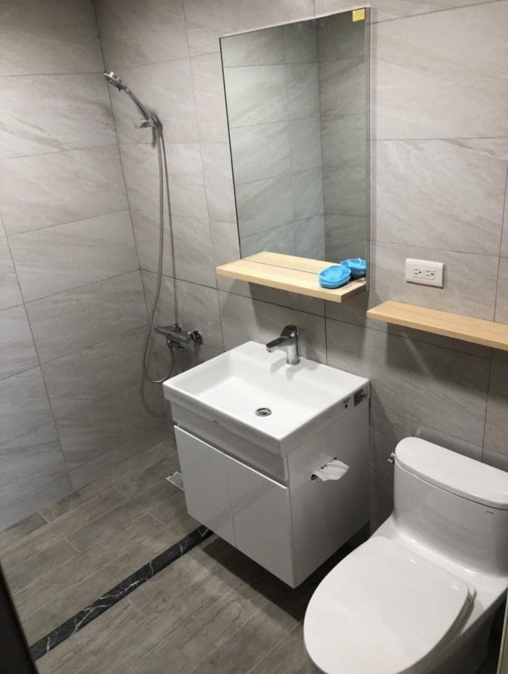 1) 照片顯示一個現代浴室,包括馬桶、洗手台、鏡子和淋浴設備