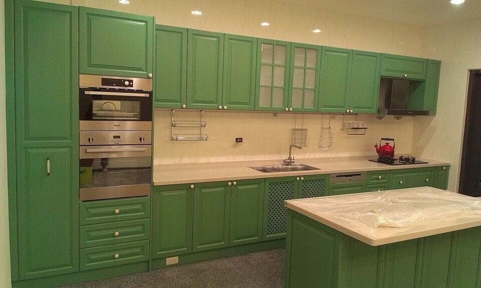 這張「廚房」的照片是綠色的櫥櫃,一個烤箱,一個水槽,一個中島,和白色的檯面。