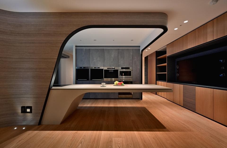 這張照片是一間現代化的廚房,最引人注目的地方是彎曲的牆壁和流線型的中島臺,營造出獨特的空間感和設計感。