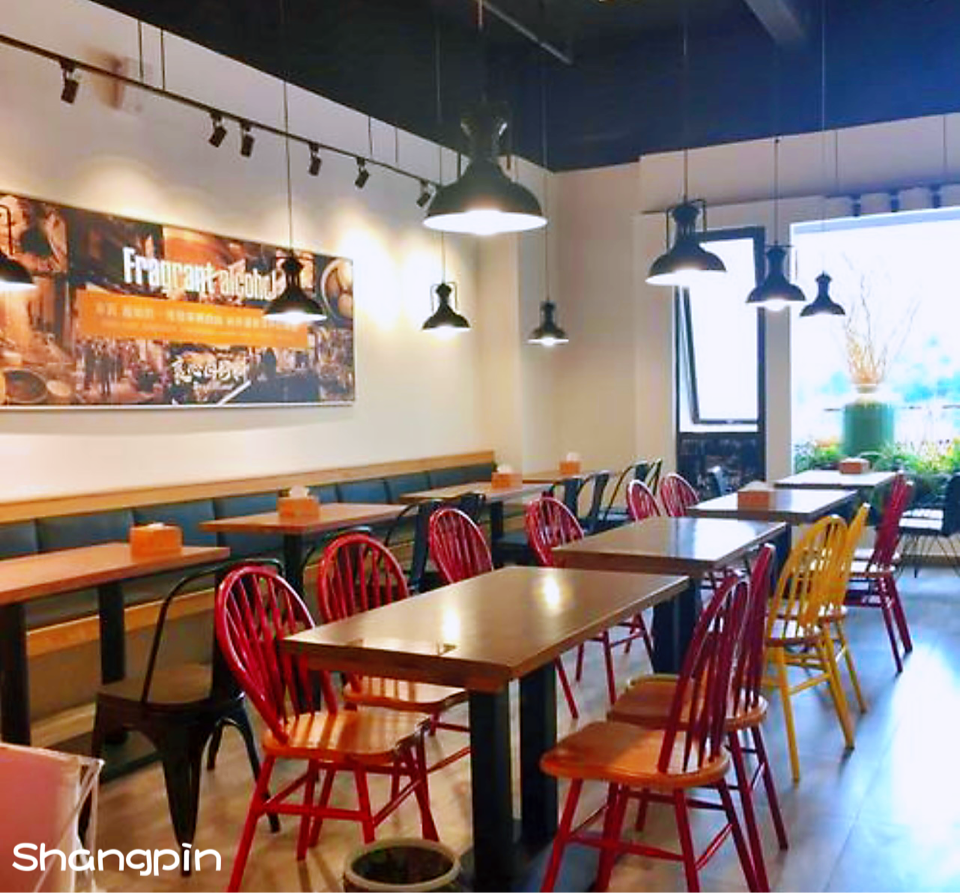 這張照片是一家餐廳的用餐區,最重要的是餐廳的裝潢風格,牆上掛著一幅現代風格的畫作,桌面是木質的,椅子是紅色的,整個環境看起來十分溫馨舒適。