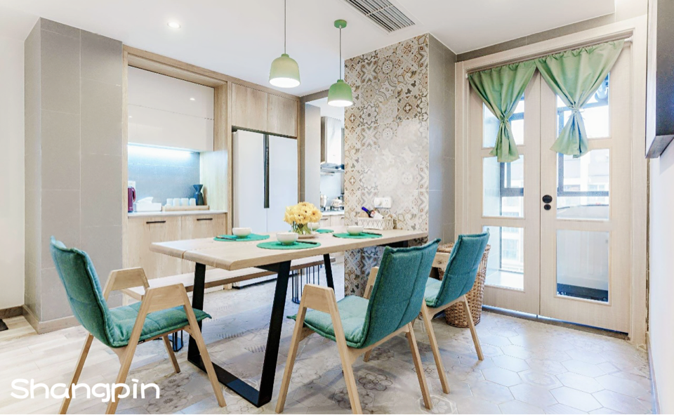 這張照片是一個現代化的廚房和餐廳,餐廳裡有一張木桌,上面擺放著花瓶,並搭配四張深藍色的椅子。