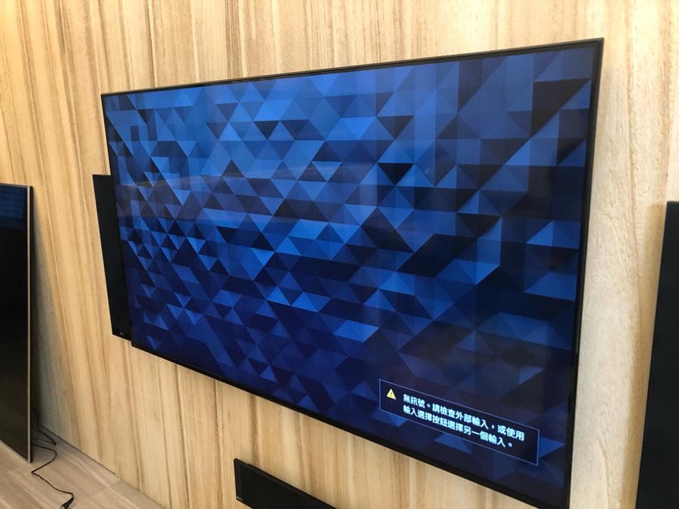 1) 照片顯示一個安裝在木板牆上的黑色電視