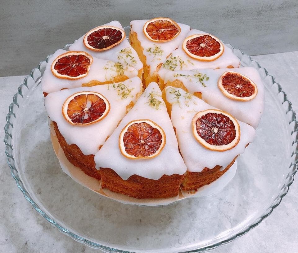 這張照片是一塊由八塊檸檬蛋糕組成的圓形蛋糕,蛋糕上覆蓋著一層白巧克力,每塊蛋糕上都有一片新鮮的檸檬片作為裝飾。