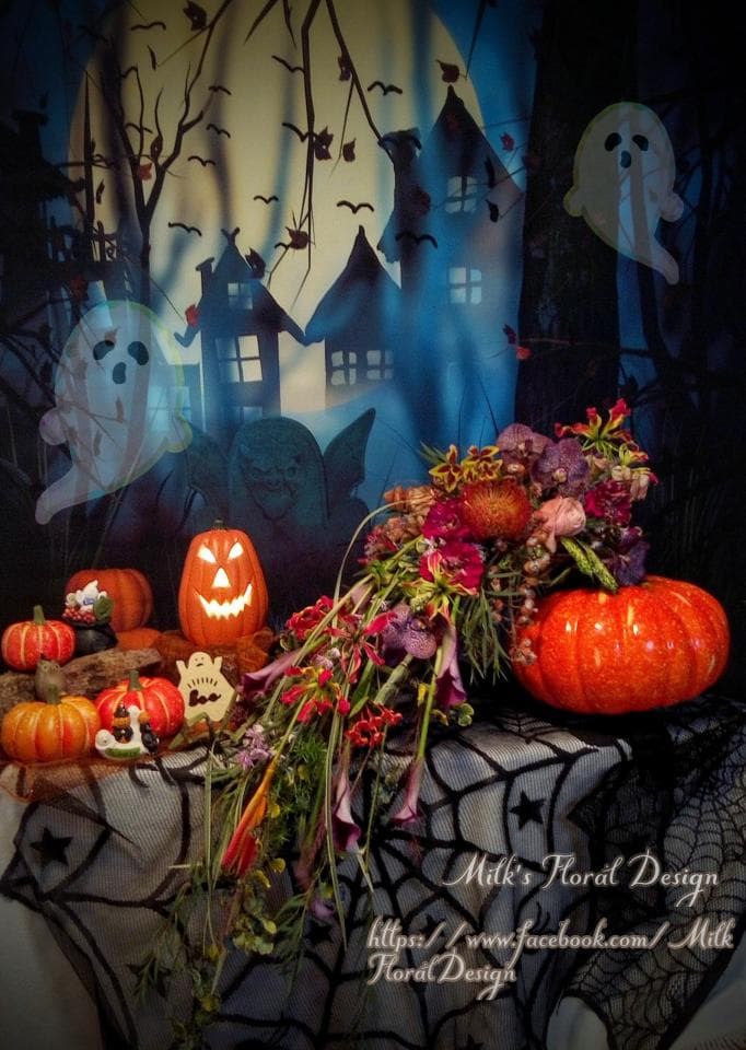 1) 照片顯示一個萬聖節主題的花束,花束上擺放著南瓜燈和南瓜,並有鬼魂和蜘蛛網的背景