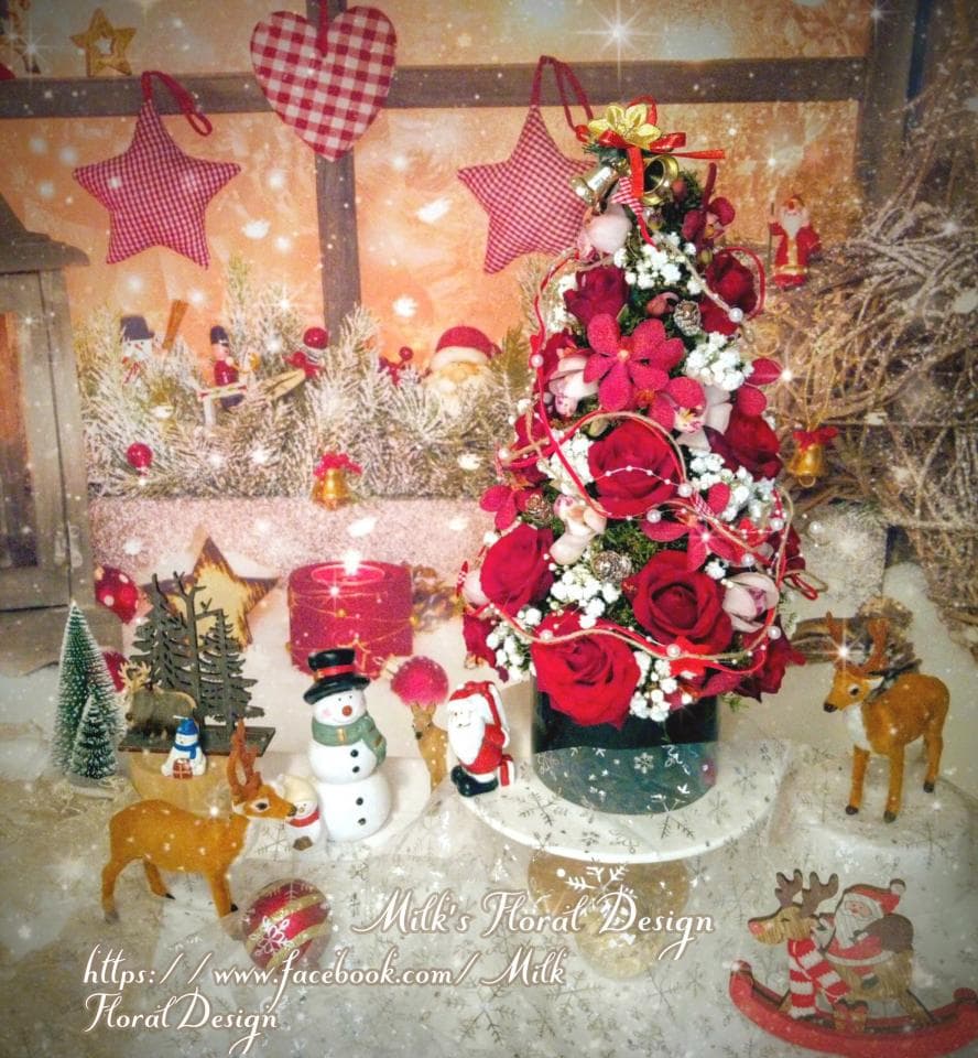1) 照片中是一個用紅玫瑰和白色小花裝飾的聖誕樹,樹底是一個圓形的托盤,周圍還有一些裝飾,包括聖誕老人、馴鹿、雪人、以及裝飾的聖誕樹