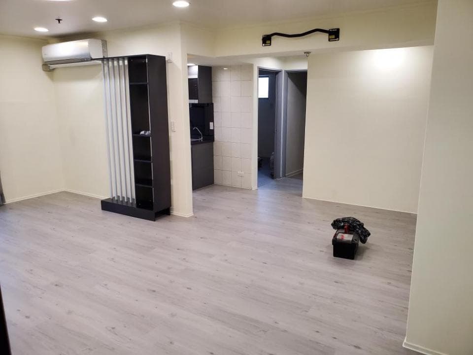 這張照片是一間有著淺灰色木紋地板的客廳,客廳中央放置了一個黑色鐵架,並有簡單的裝飾。