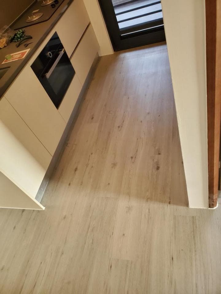 1) 照片顯示一個廚房的一部分,其中有白色櫃子和一個嵌入式烤箱,以及部分淺色木紋地板