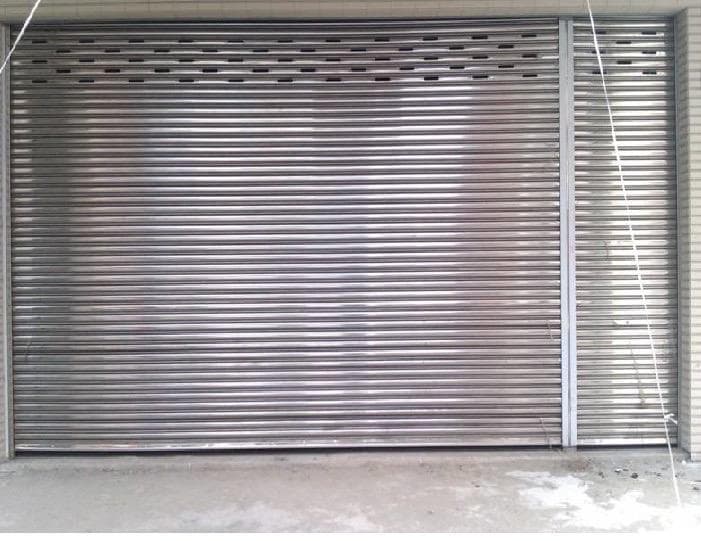 這張照片是一道銀色的金屬捲門,它被關閉著,看起來很堅固,上面有許多小洞。