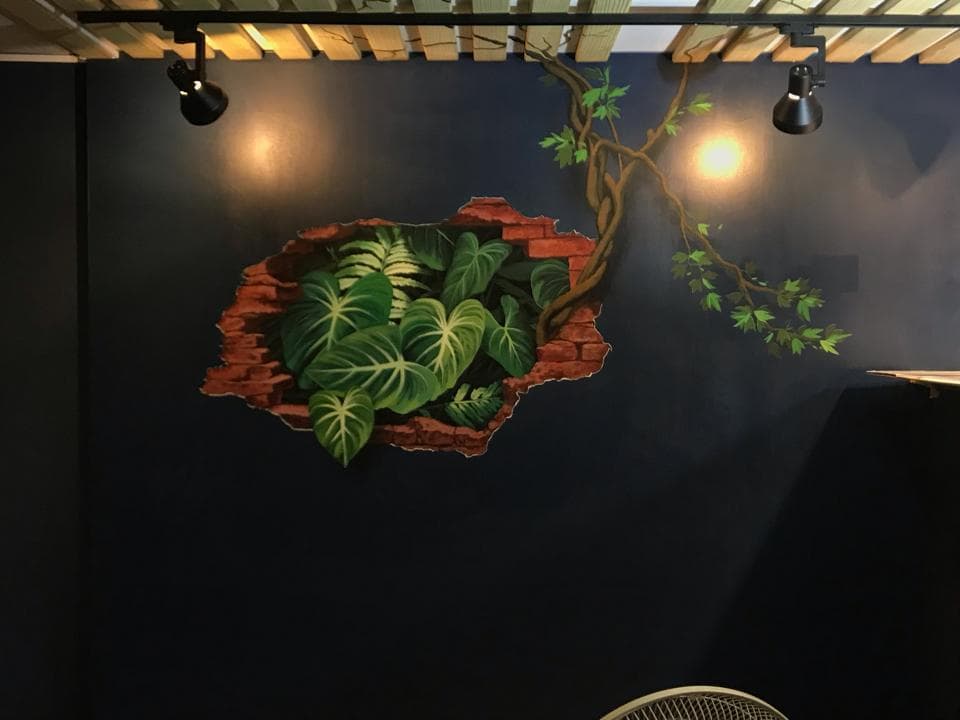 這張「牆壁」的照片是藍色的,上面有一幅壁畫,畫的是藤蔓植物和一些綠色植物從牆上長出來,看起來像是穿透了牆壁。