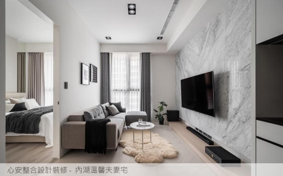 這張照片是一間現代化的客廳,最重要的是電視牆。電視牆採用大理石紋路,搭配大尺寸電視,讓客廳更顯大器。